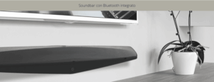 Soundbar nera sotto TV, accanto pianta